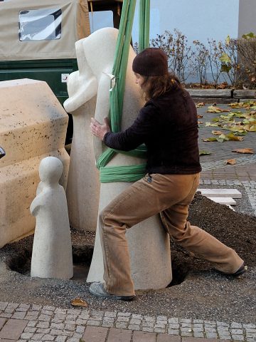 Eine Figur wird am Denkmal positioniert